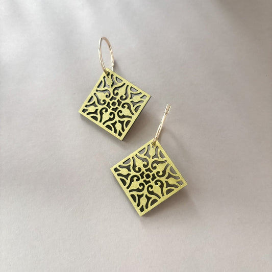 Gold square earrings with intricate patterns on a light gray background